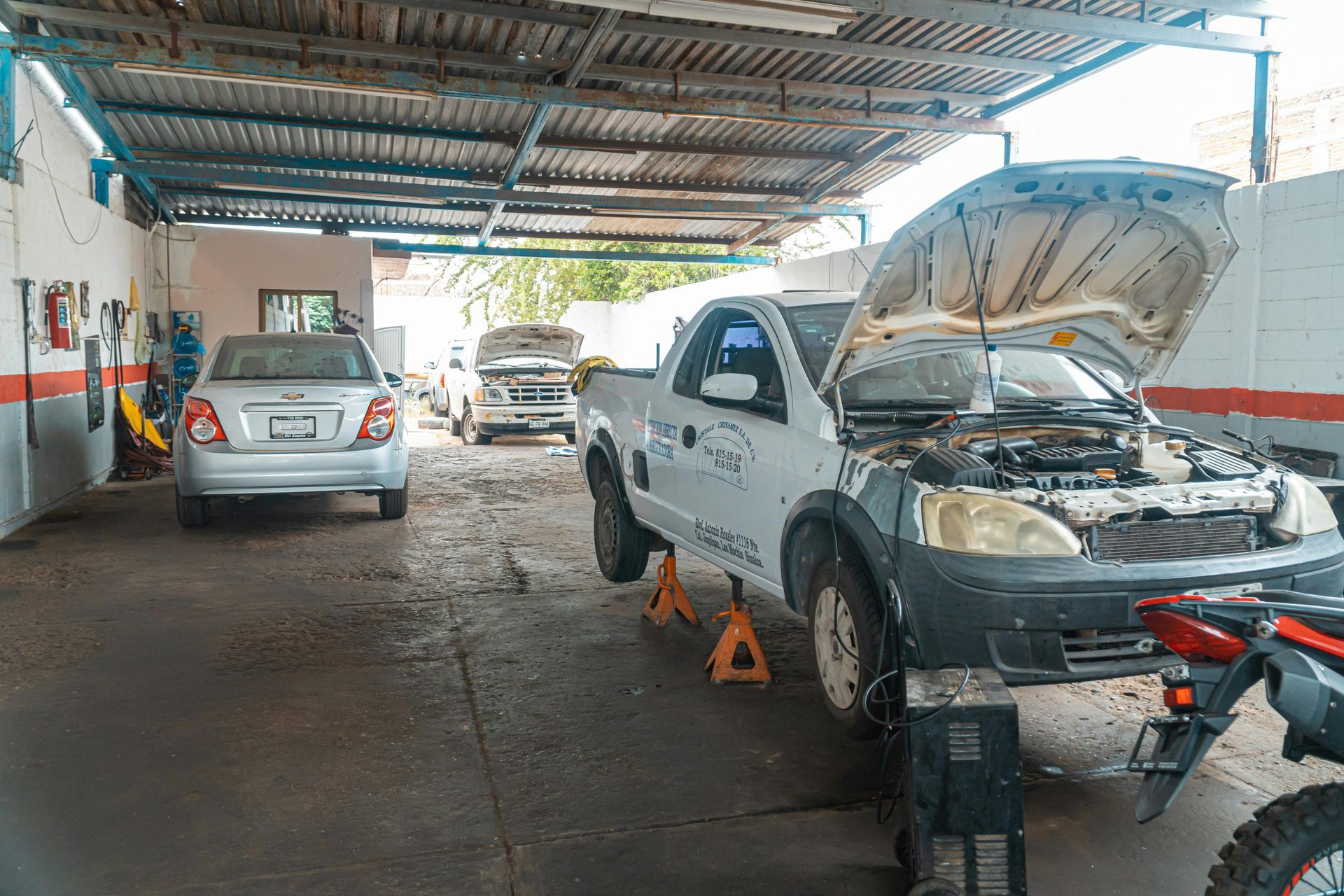 A car is being worked on in a garage with the hood open.