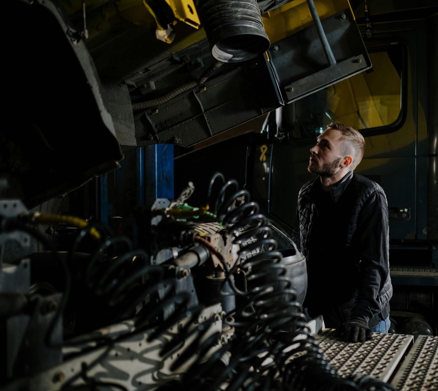 A man is working on a truck in a dark room.