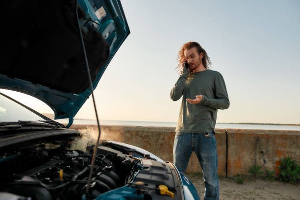 A Man Is Standing Next to a Broken-Down Car and Talking on a Cell Phone — Pearl, MS — Hall’s Towing Service