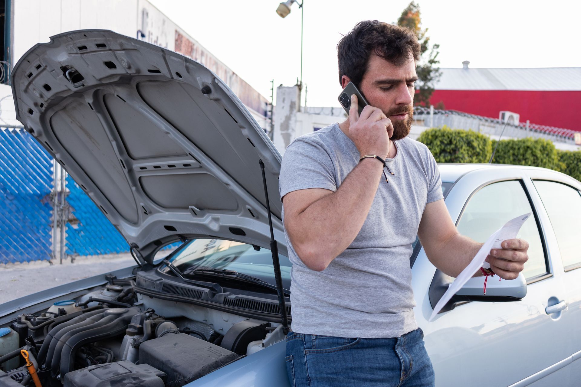 A Man Is Talking on a Cell Phone Next to a Broken Down Car — Pearl, MS — Hall’s Towing Service