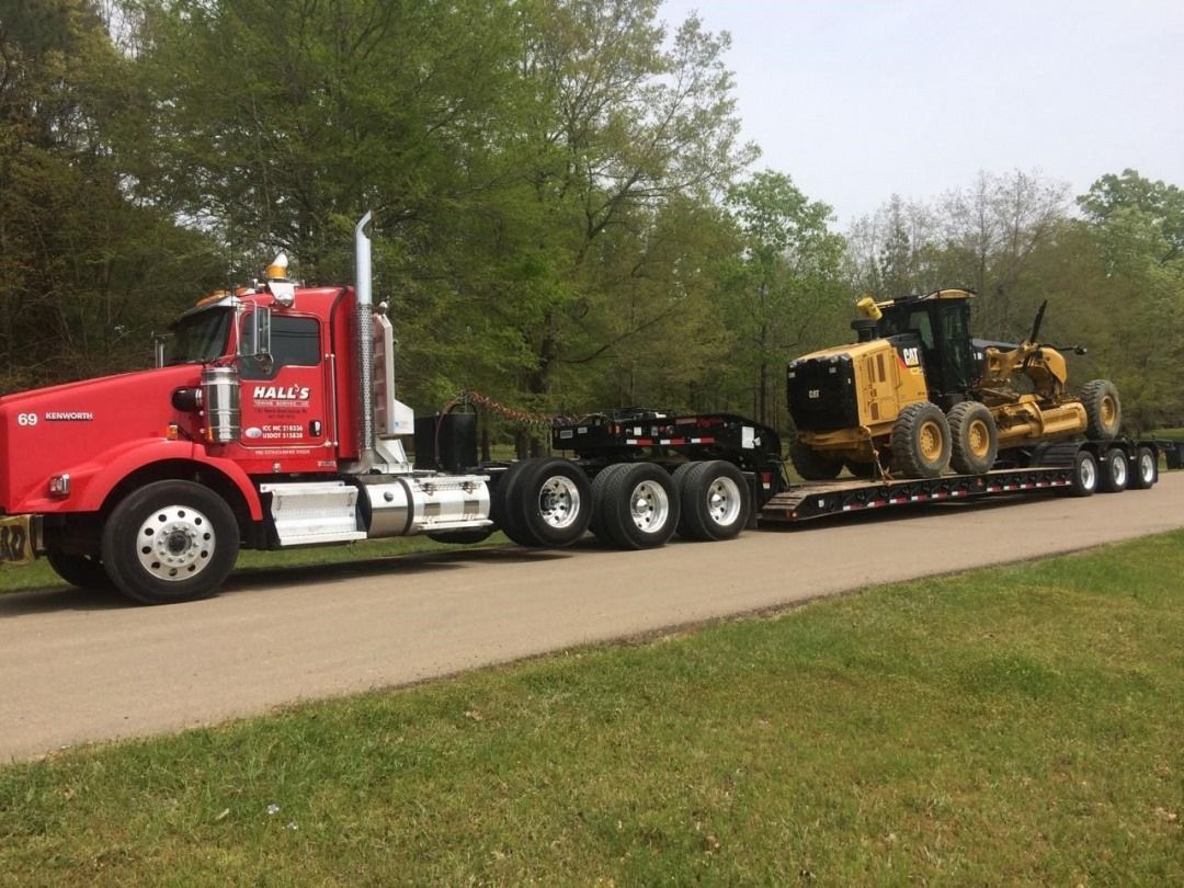 A Truck Is Carrying an Excavator on a Trailer on a Highway — Pearl, MS — Hall’s Towing Service