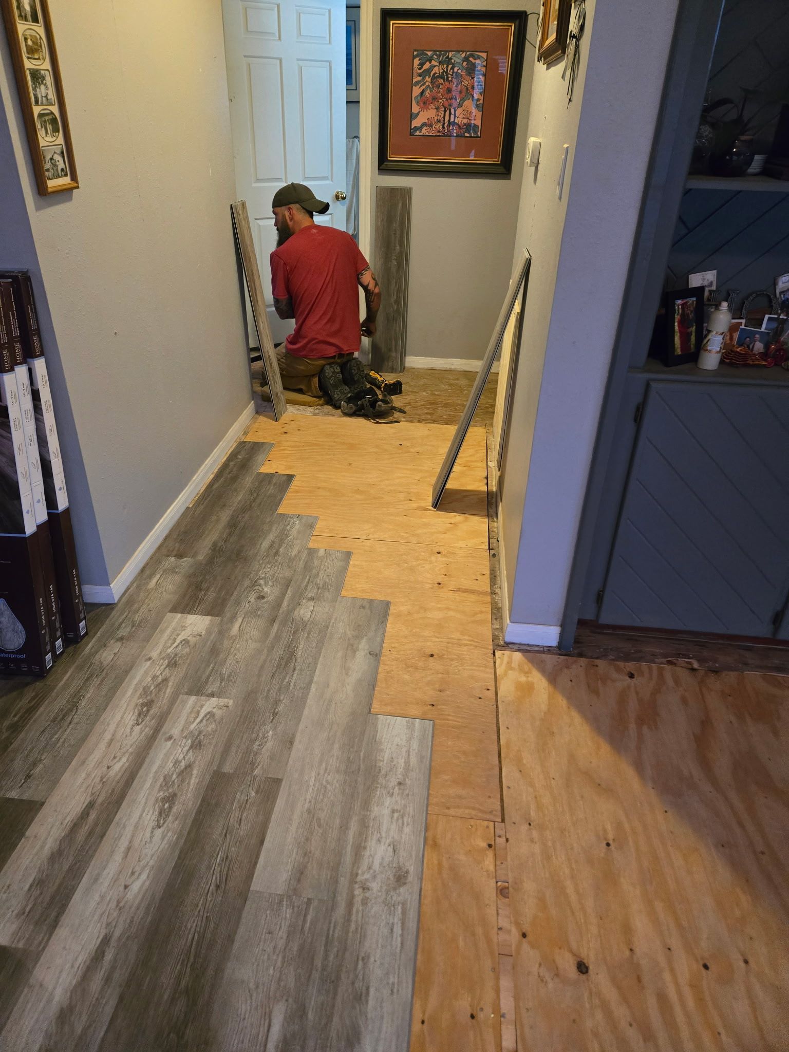 A man is installing a wooden floor in a hallway.