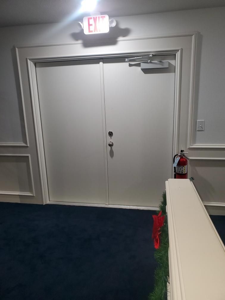 A fire extinguisher is next to a white door in a hallway.