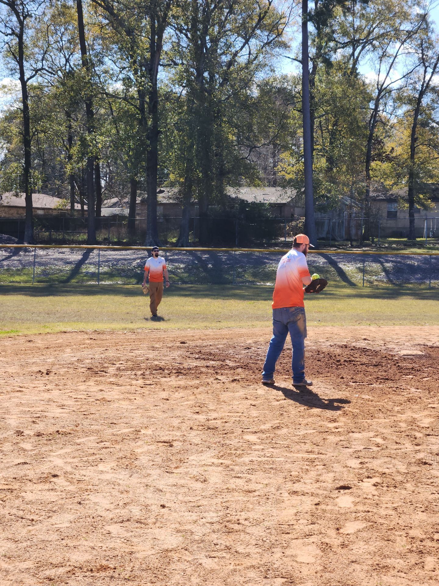 Two men are playing baseball on a dirt field.