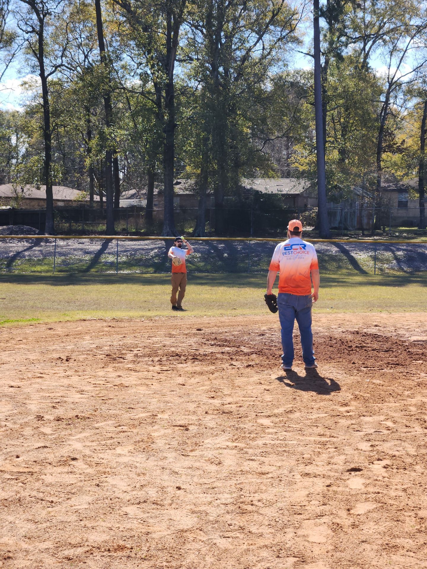 Two men are playing baseball on a dirt field.