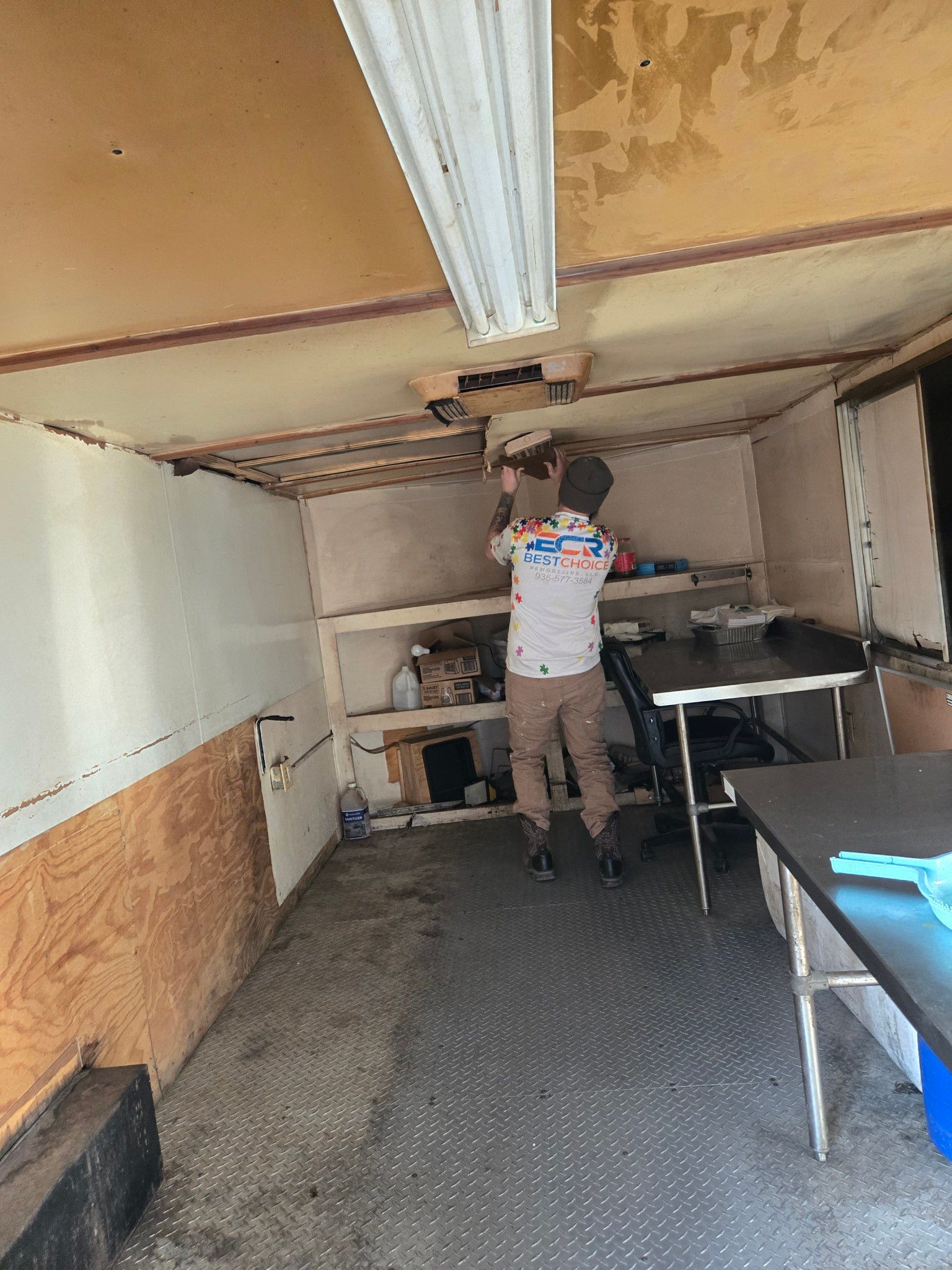 A man is working on the ceiling of a trailer.