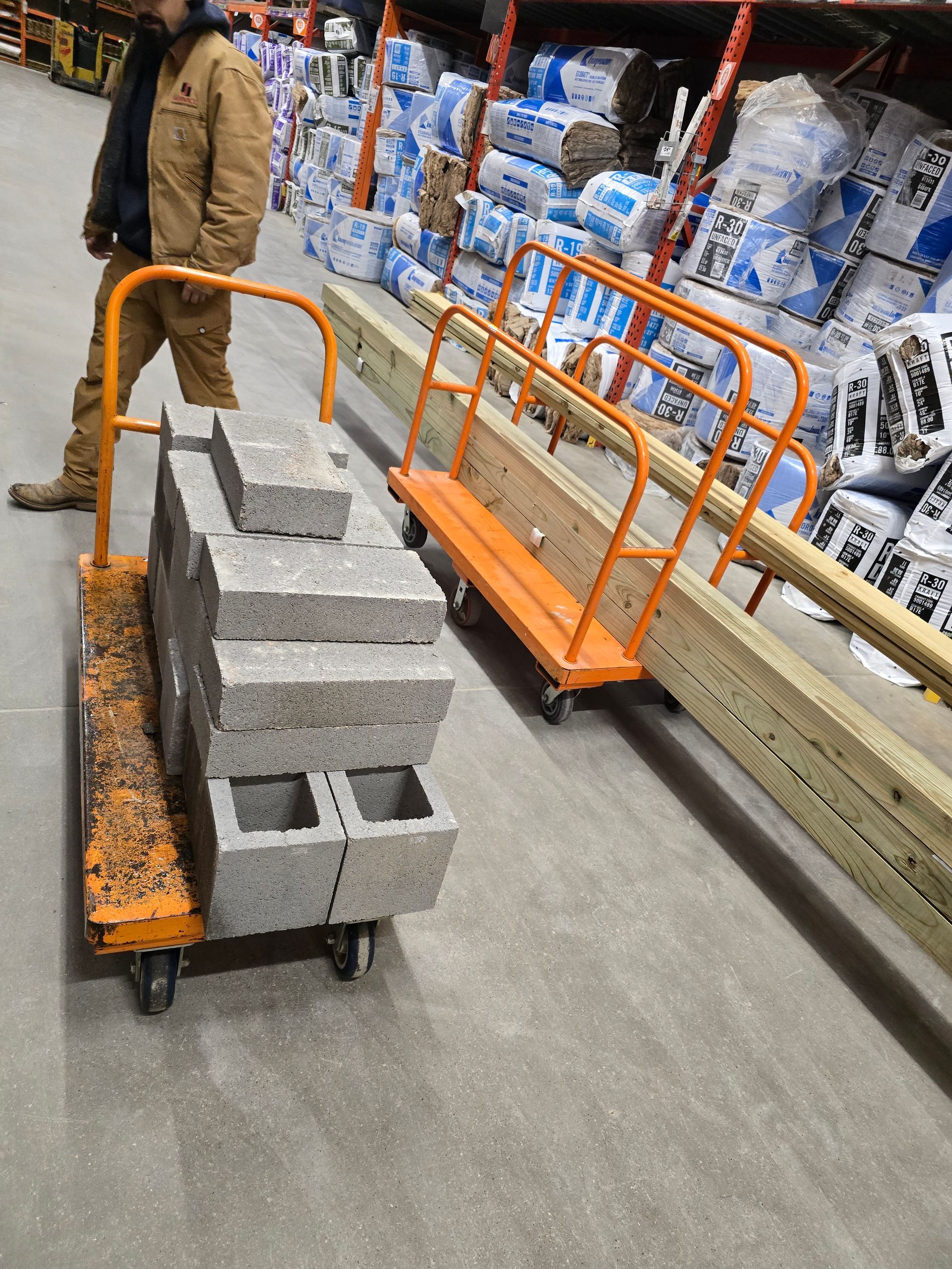 A man pushing a cart full of bricks in a warehouse