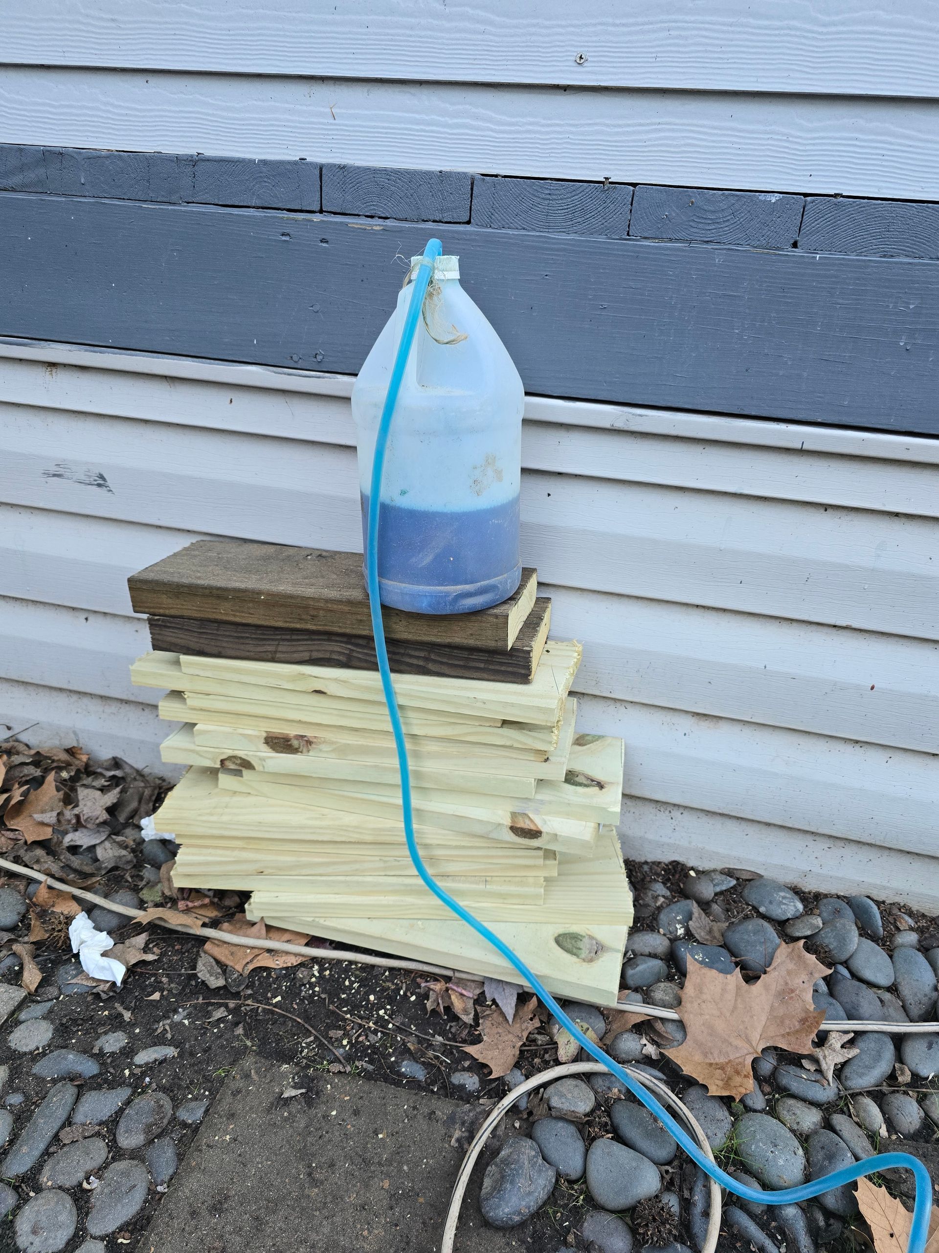 A gallon of blue liquid is sitting on top of a pile of wood.