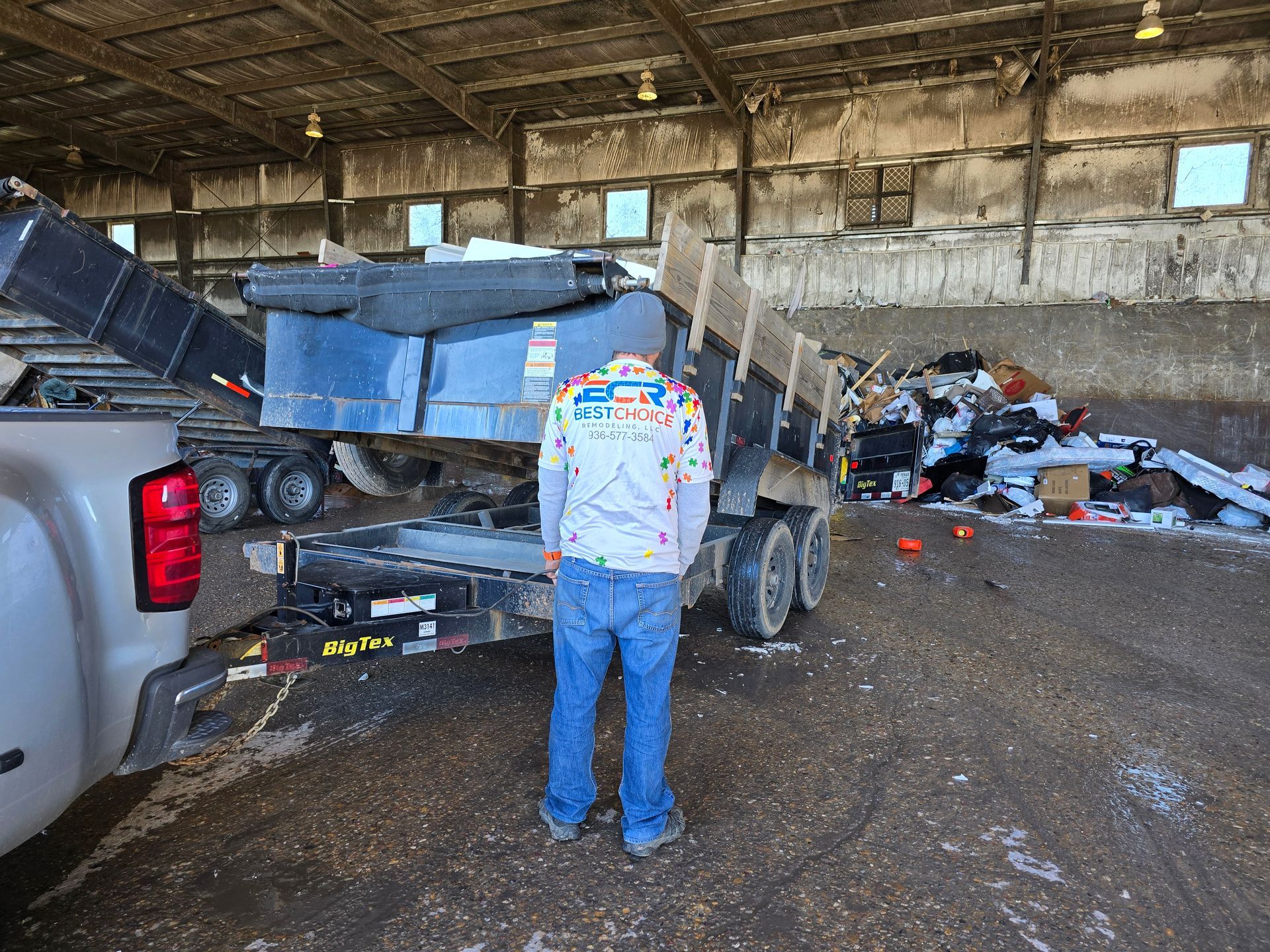 A man is standing next to a dumpster in a warehouse.