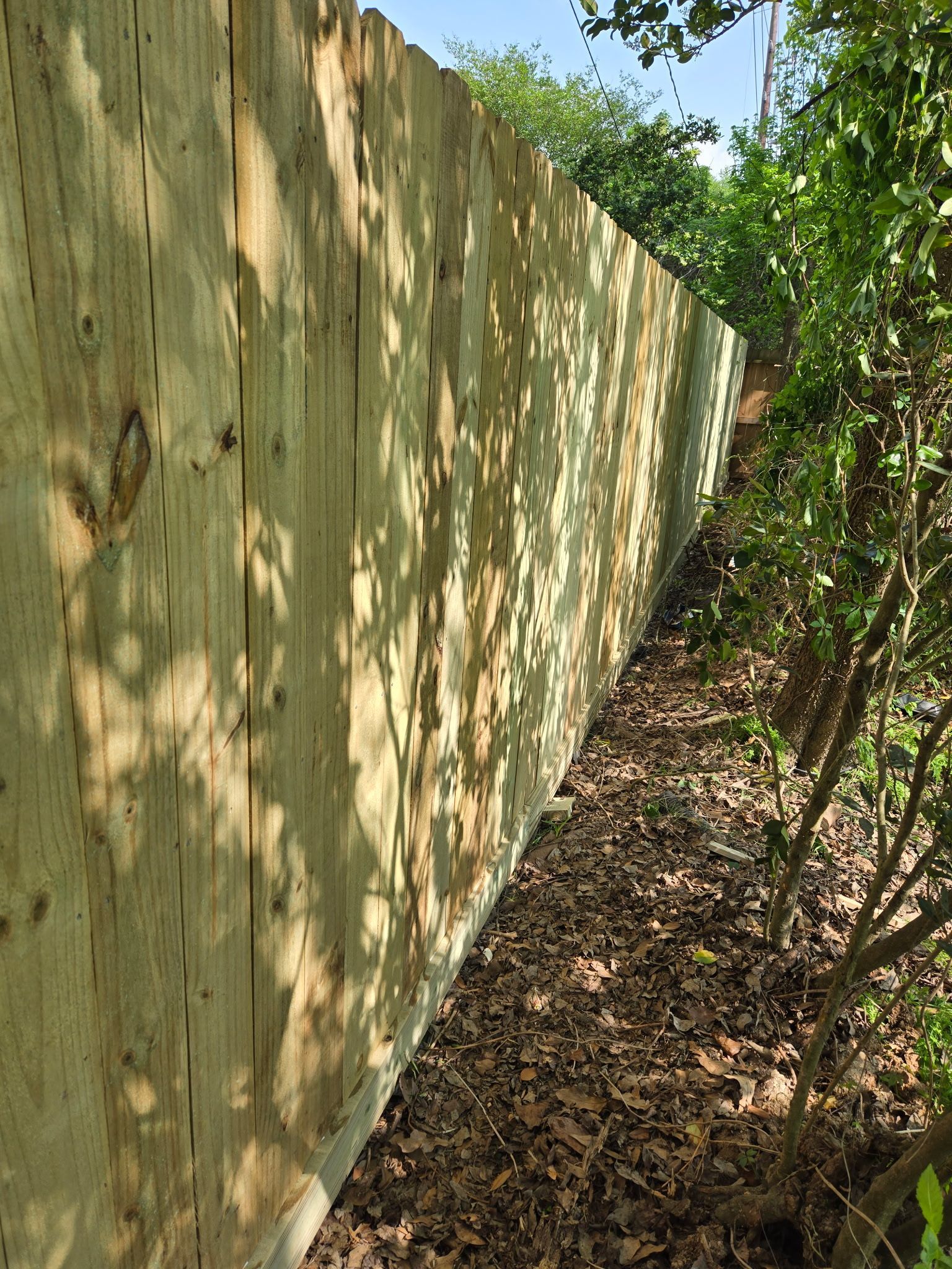 A wooden fence is surrounded by trees and leaves.