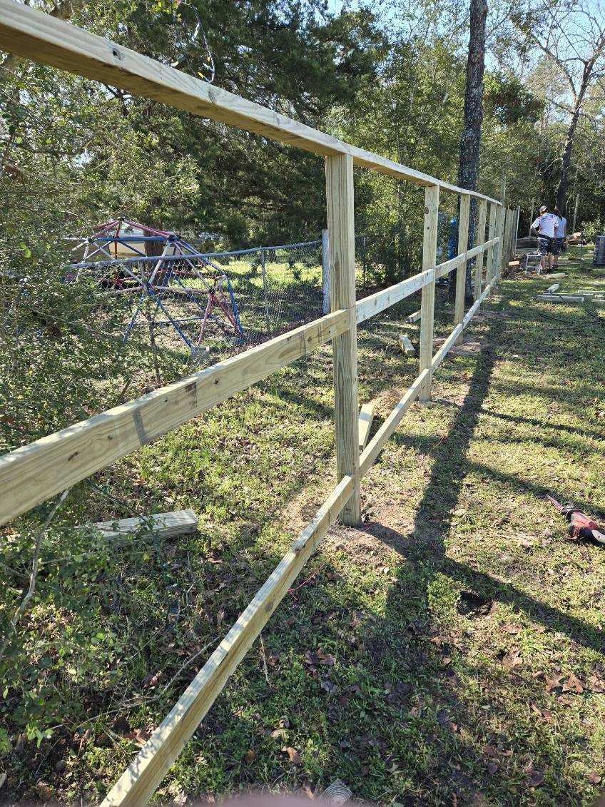 A wooden fence is being built in a grassy field.