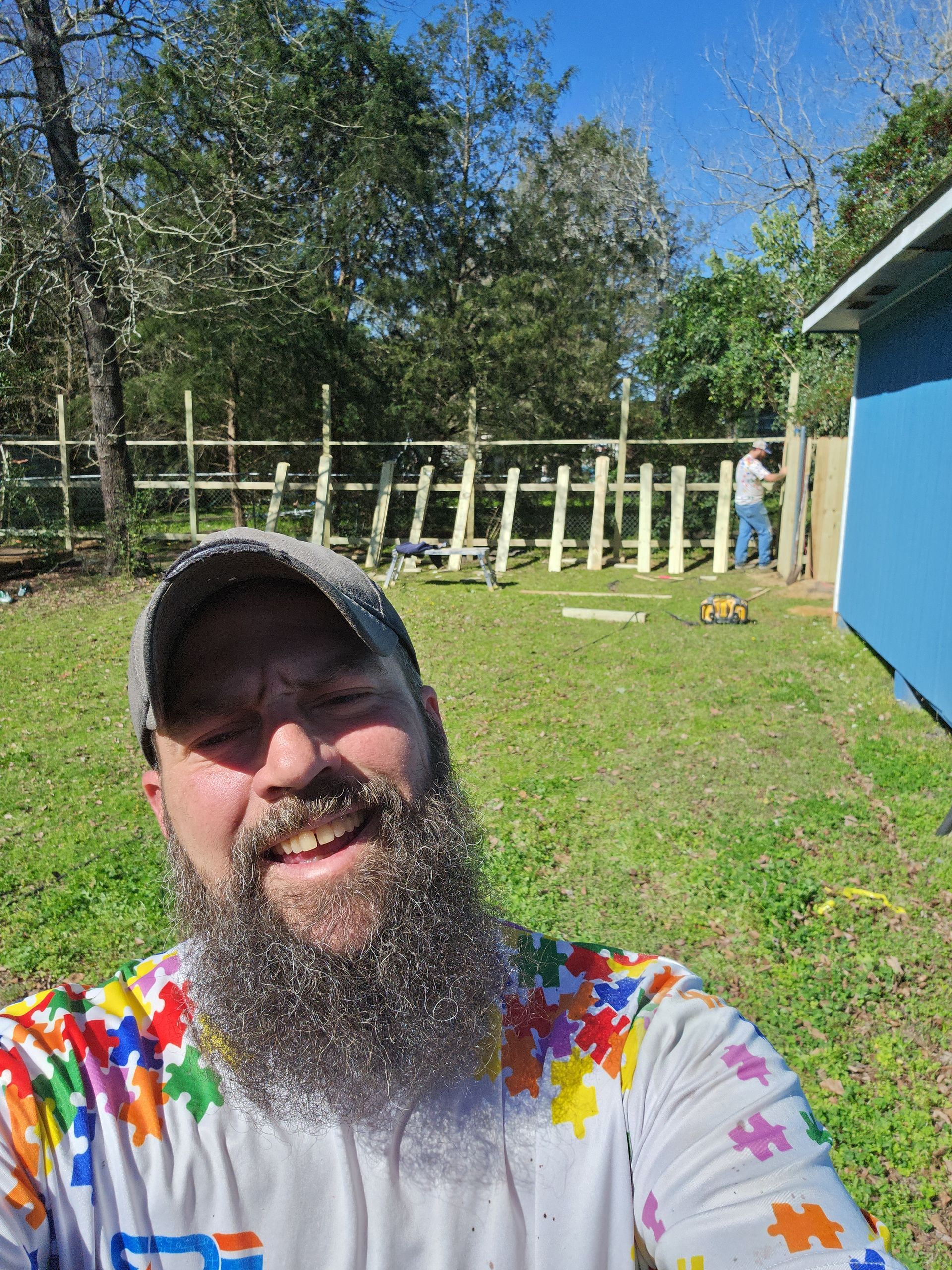 A man with a beard is taking a selfie in a field.