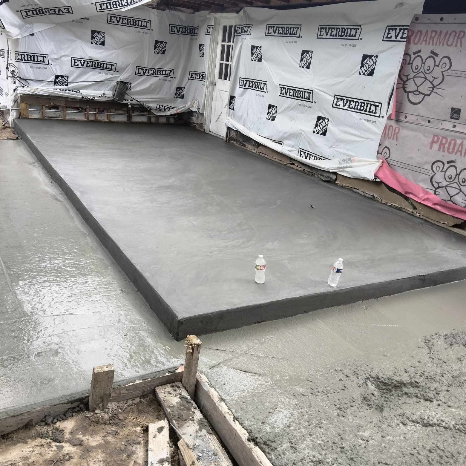 Two bottles of water are sitting on a concrete slab