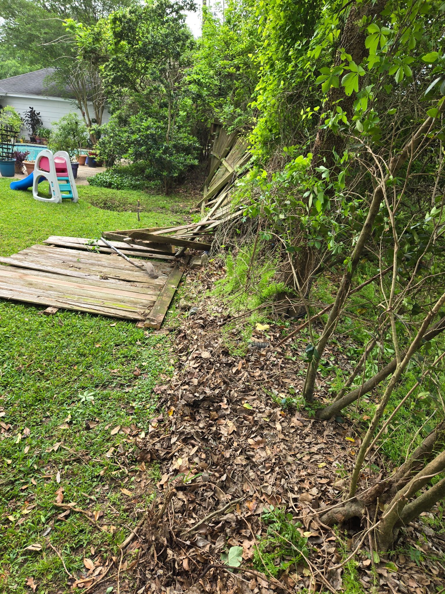 A wooden fence is sitting in the middle of a yard surrounded by trees.
