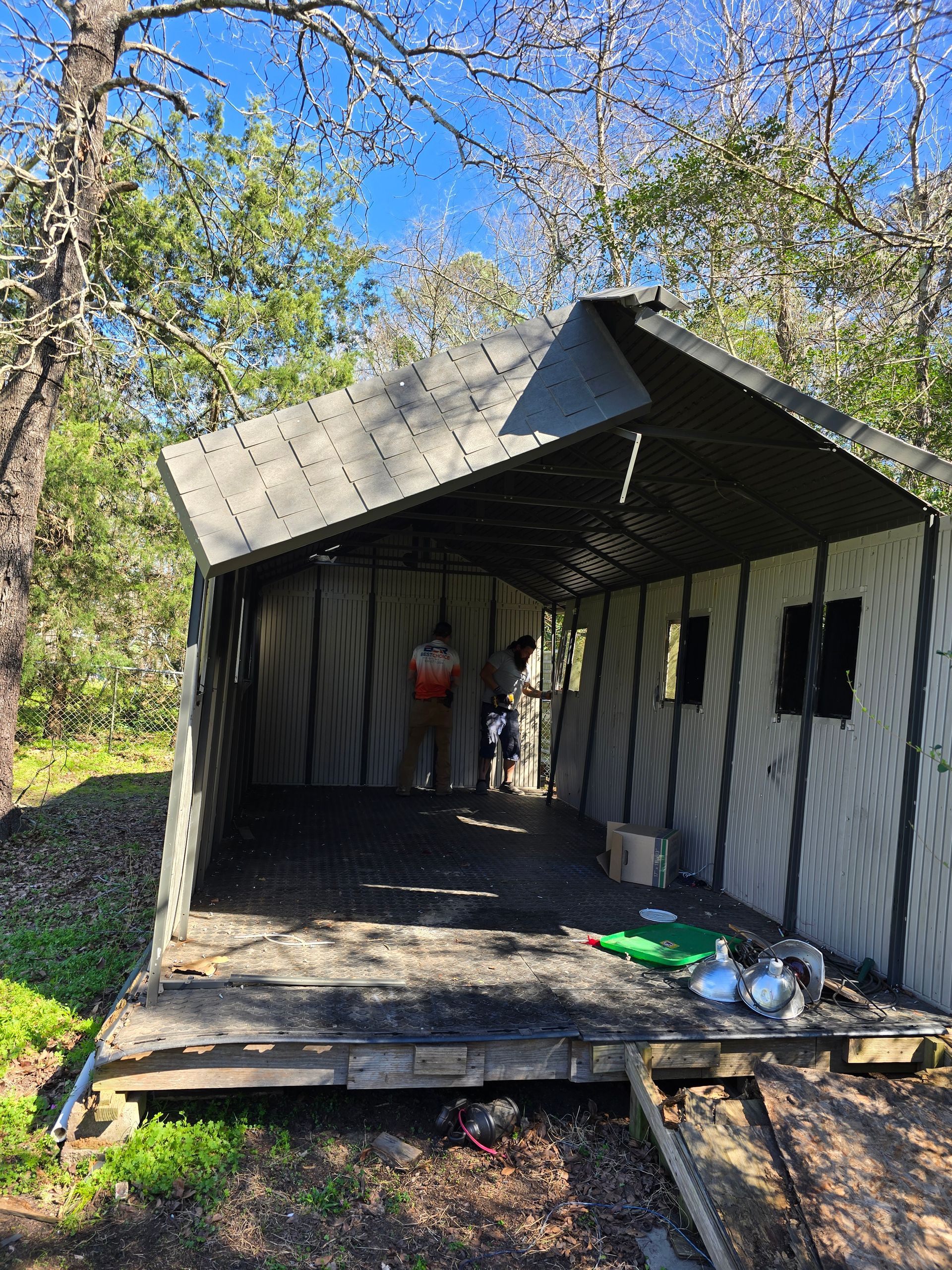 A group of people are standing inside of a shed in the woods.
