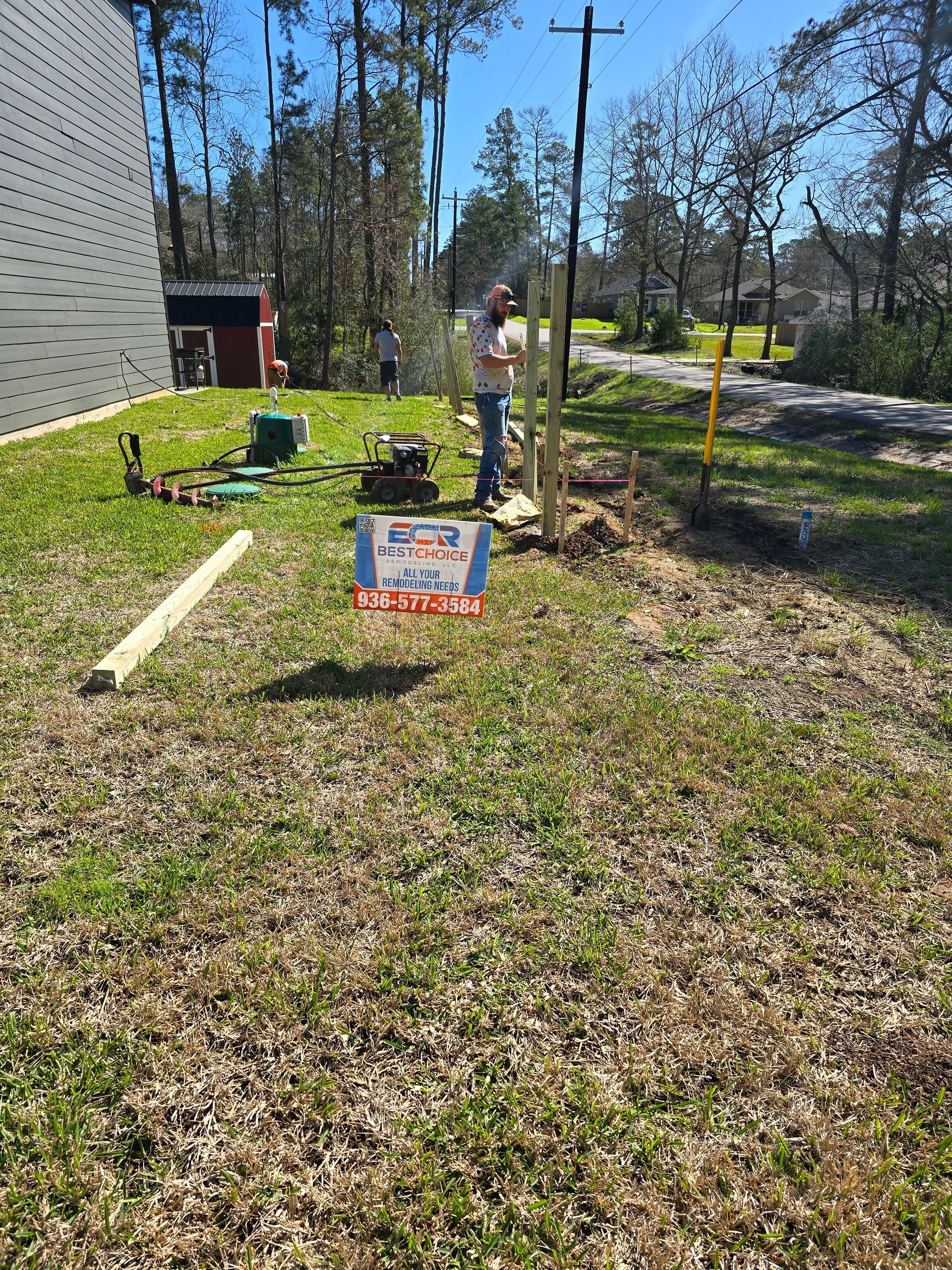 A man is standing in the grass next to a sign that says for sale.