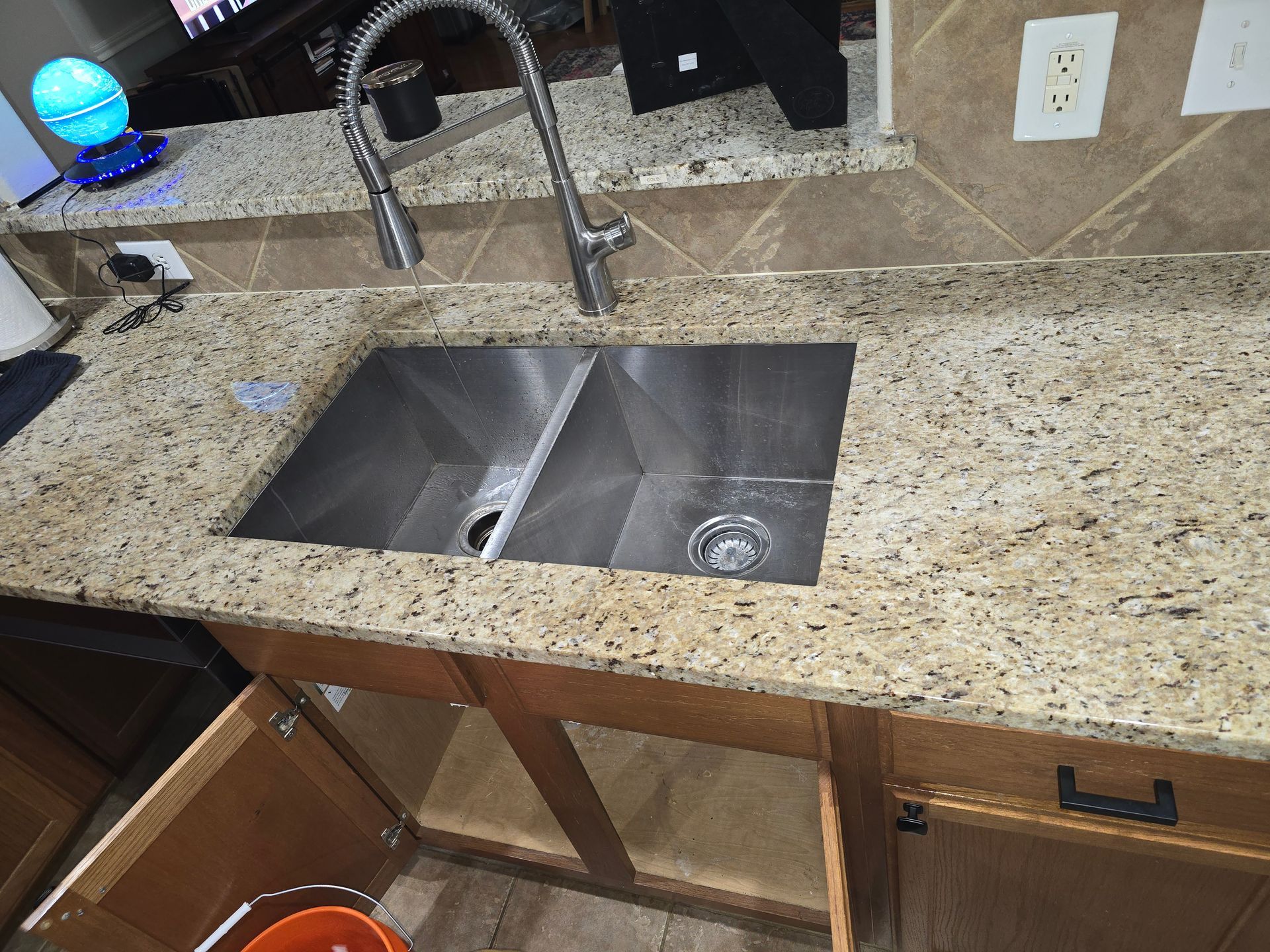 A kitchen sink with a faucet on top of a granite counter top.