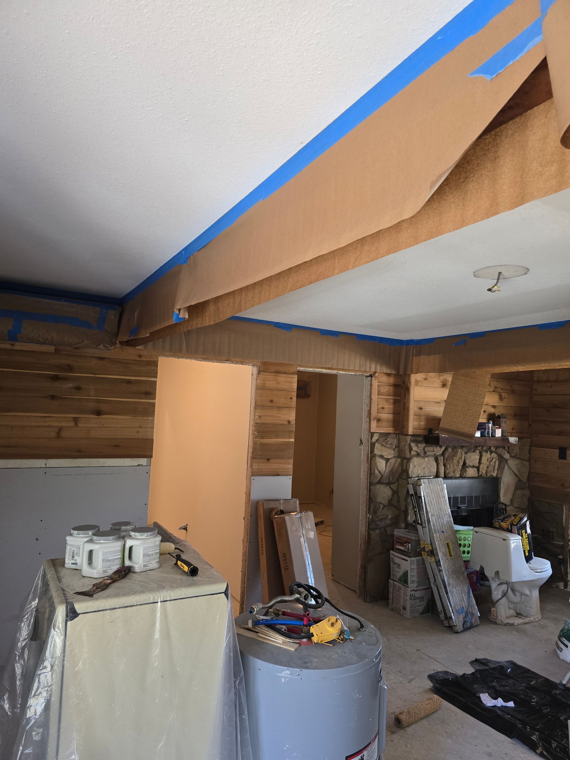 A room that is being painted with blue tape on the ceiling