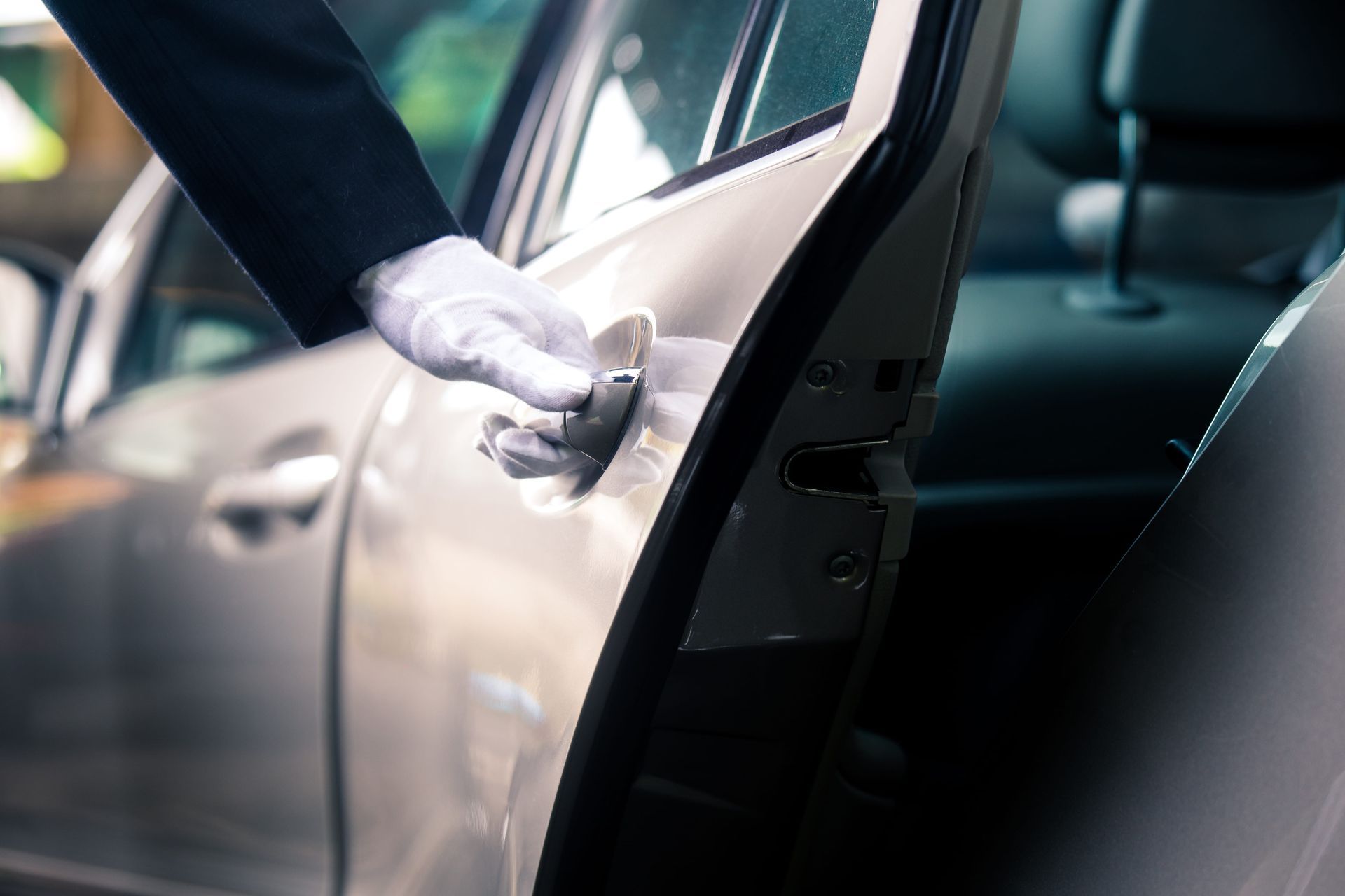 A man in a tuxedo is opening the door of a car.