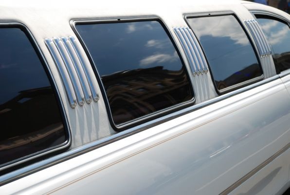 The side of a white limousine with a lot of windows.