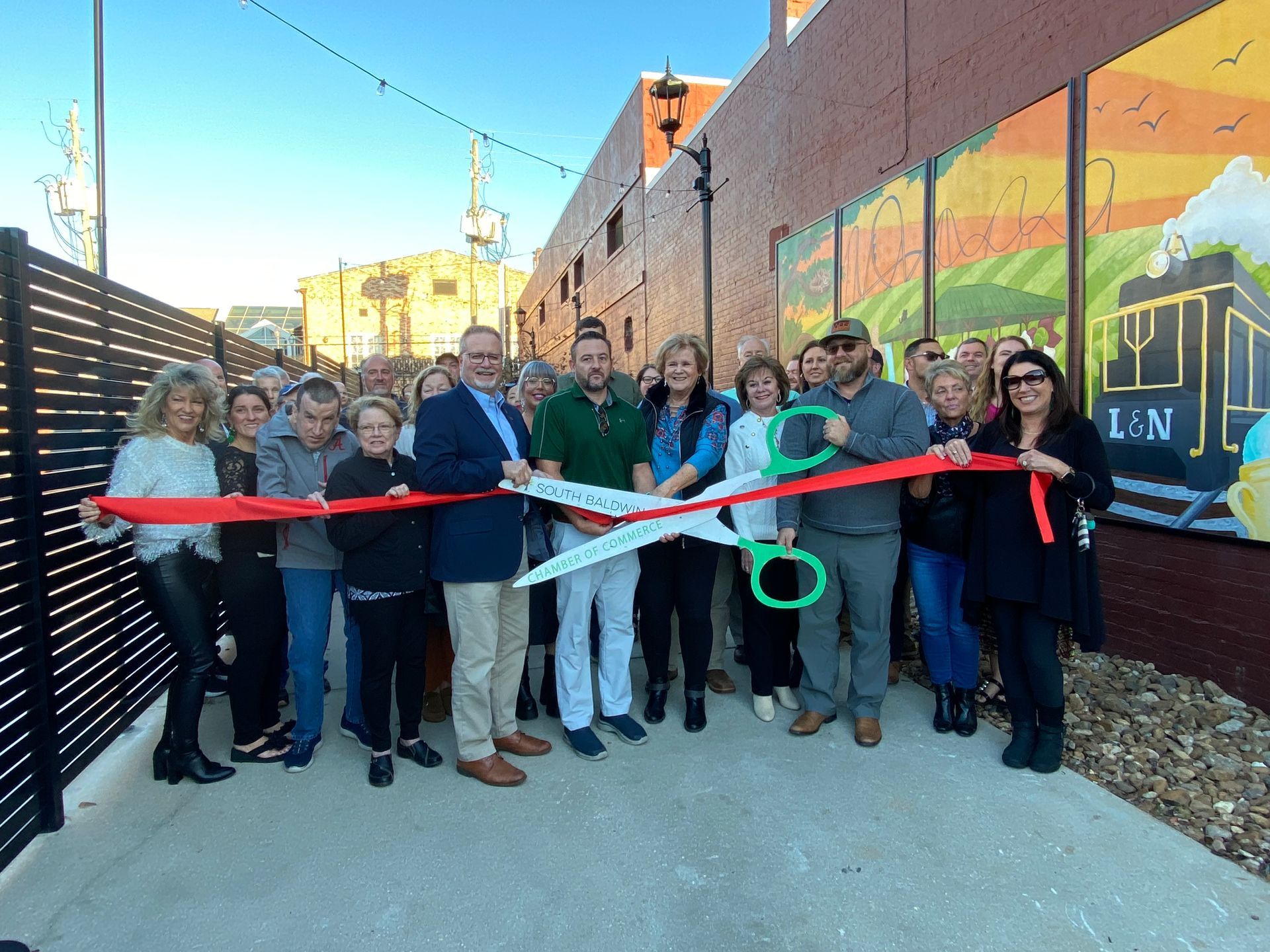 Foley Main Street members and city officials dedicate the Cat Alley walkway Thursday, Nov. 21. The walkway includes lights, murals and tables and connects the Cat Alley art area with North Alston Street.