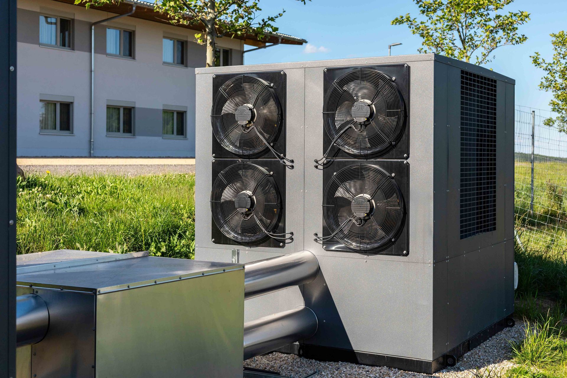 Large, gray industrial unit with four fans, outside a building.