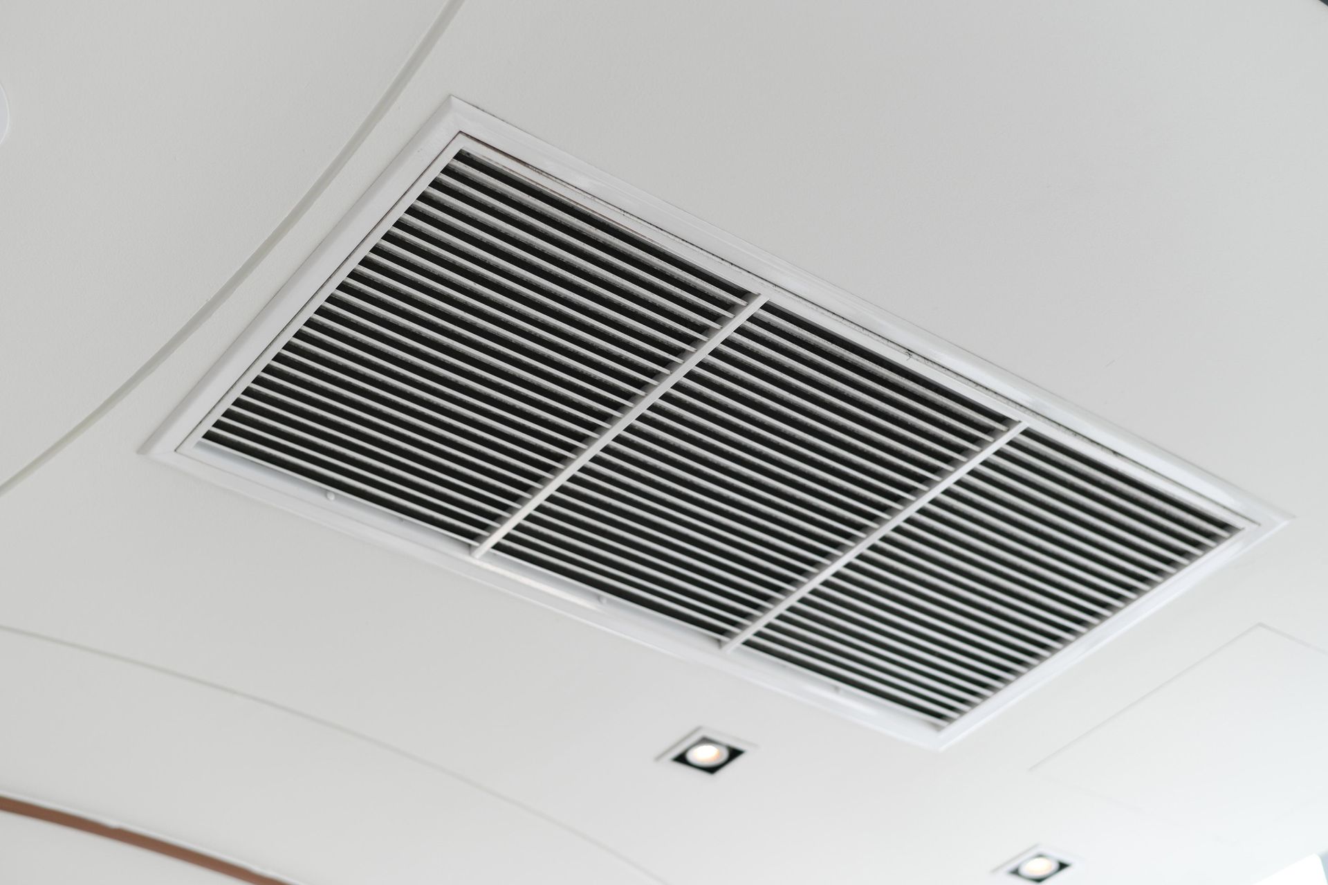 Ceiling air vent with metal slats, recessed in a white ceiling.
