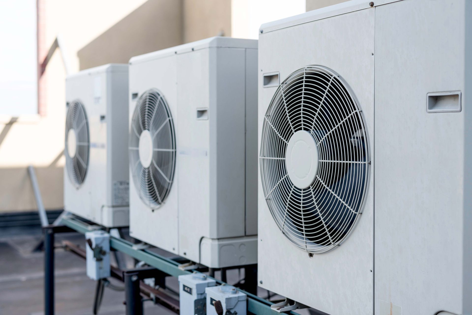 Three white air conditioning units on a rooftop.