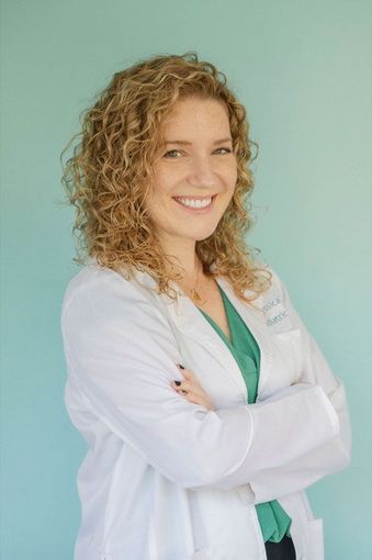 Photo of Dr. Jessica Duggan, DPM wearing a white coat over a pink blouse