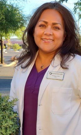 Photo of Monica Lopez, FNP wearing a white coat over a purple blouse