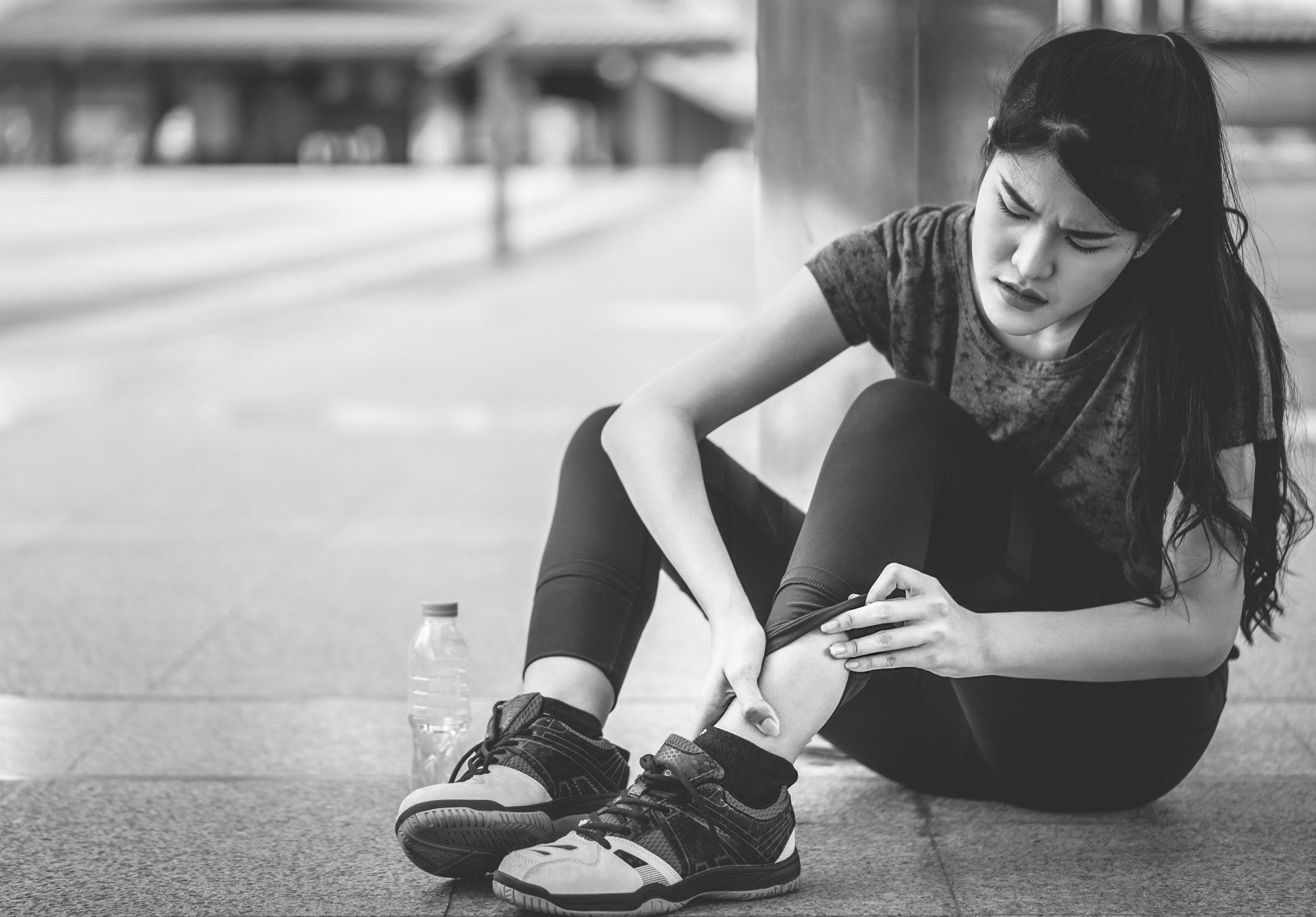 black and white photo of a young woman with ankle injury while exercising