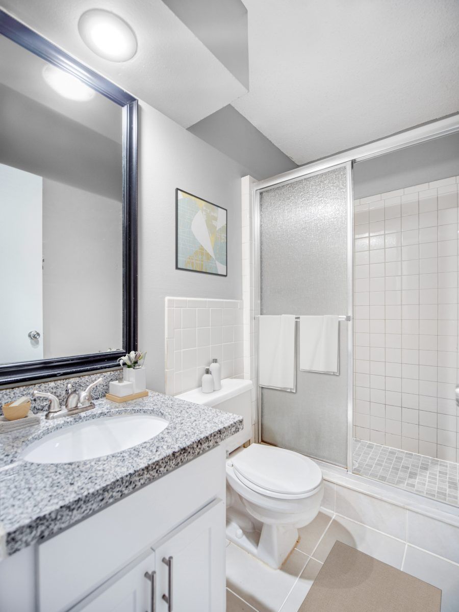 A bathroom with a toilet a sink and a shower at Veridian of Melbourne Townhome Apartments in Melbourne, FL.
