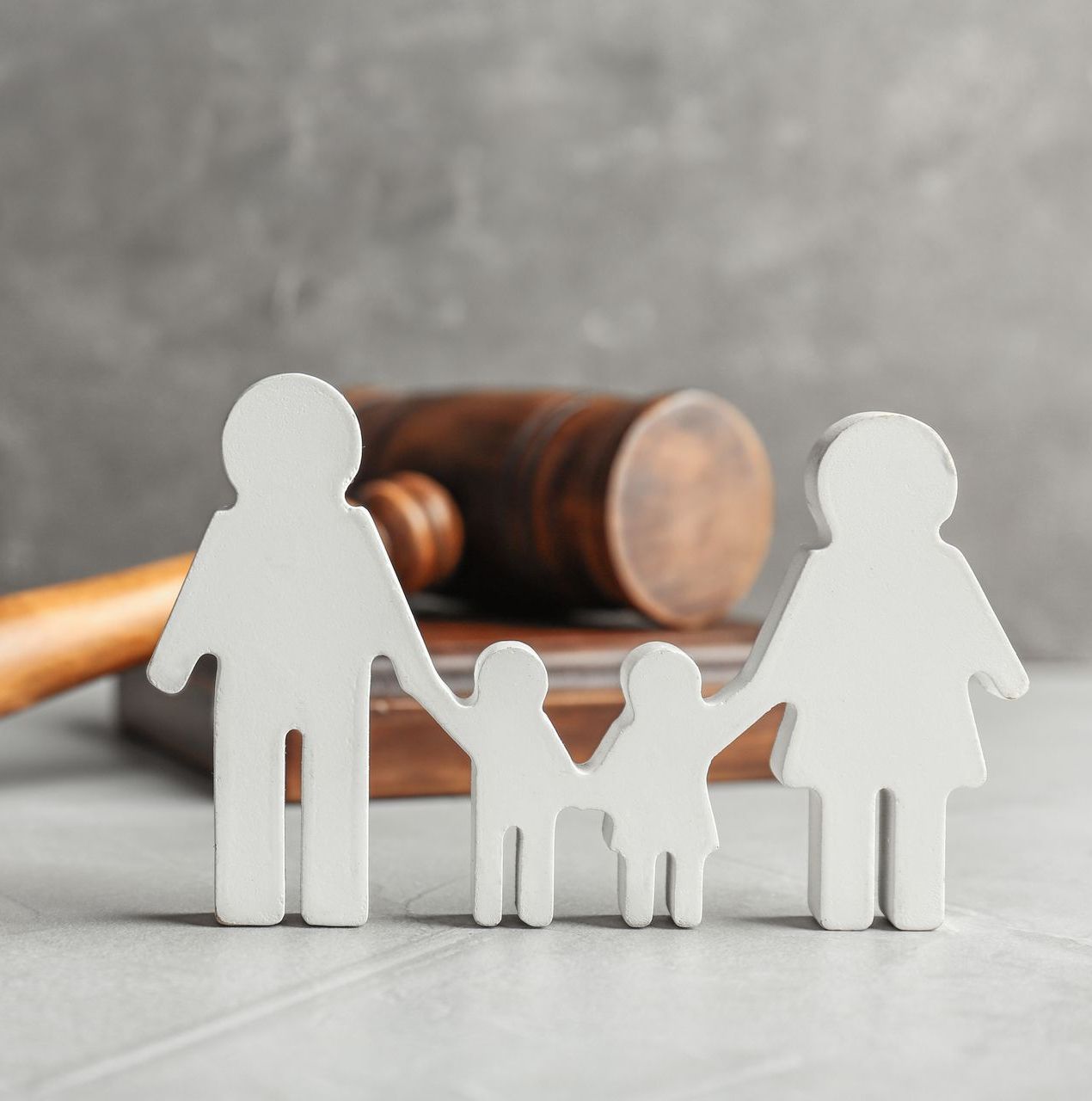 A family is holding hands in front of a wooden gavel.