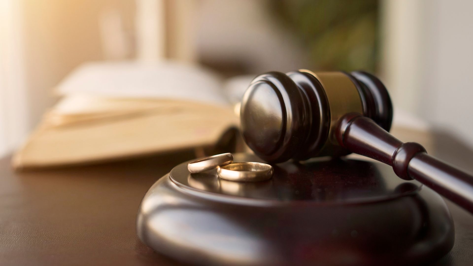 A couple of wedding rings sitting on top of a wooden gavel on a table.