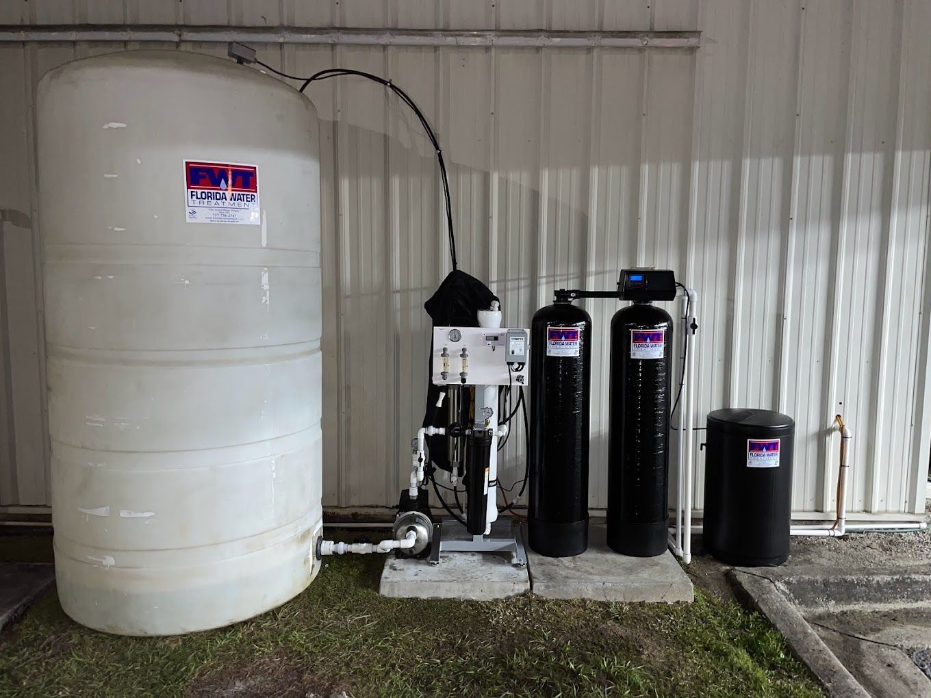 A large white tank is sitting next to two black water filters.