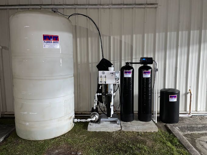 A large white tank is sitting next to three black tanks.