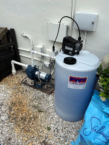 A water pump is sitting next to a large tank.