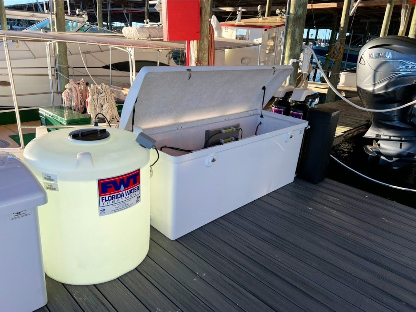 A boat is docked at a marina with a large white cooler in front of it