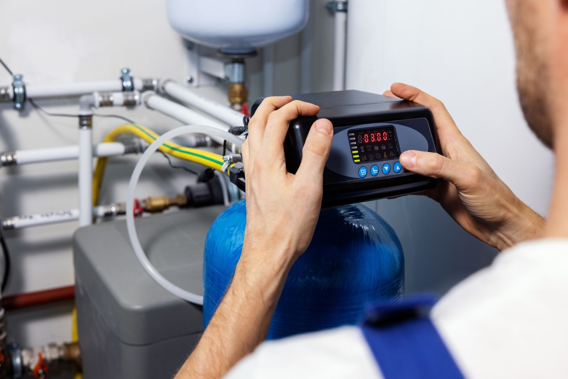 A man measuring water pressure for water softener system installation with a digital meter.