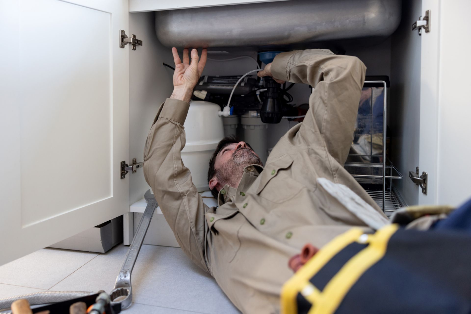 Water treatment specialist installing reverse osmosis water system under kitchen sink.