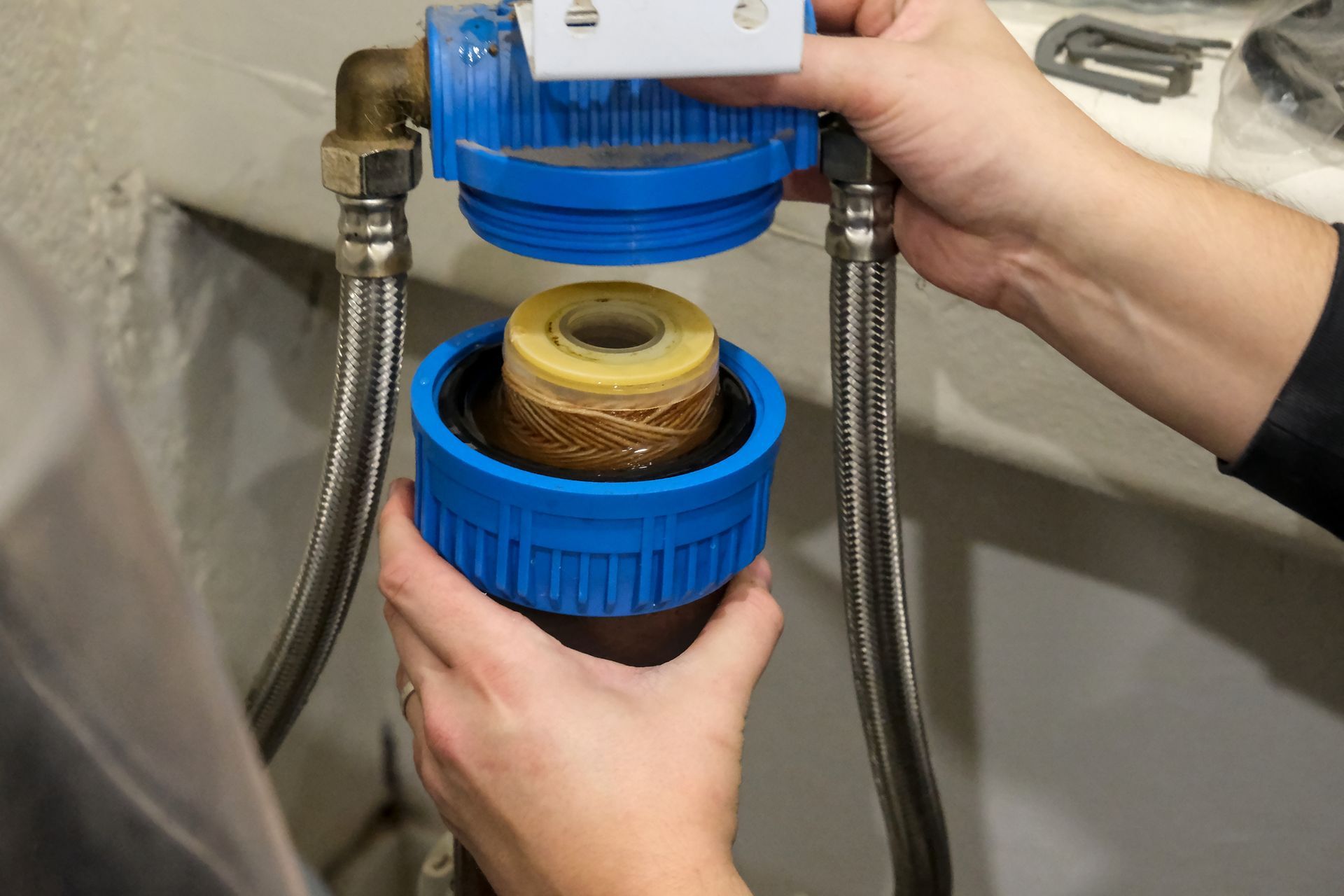 Close-up of two hands holding a water softener cartridge that needs to be replaced.
