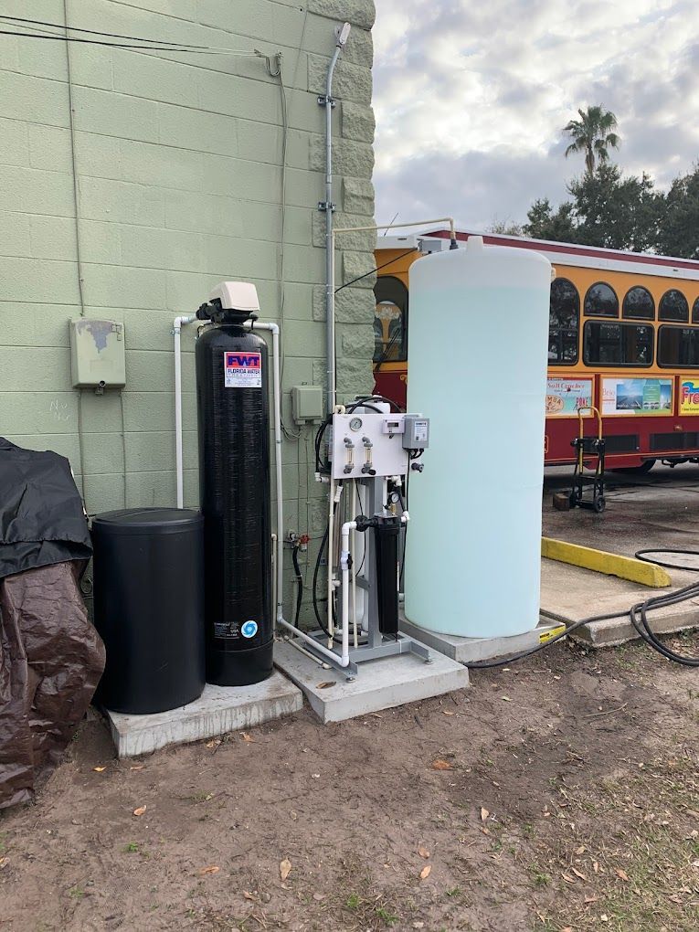 A water filter is sitting on the side of a building next to a large tank of water.