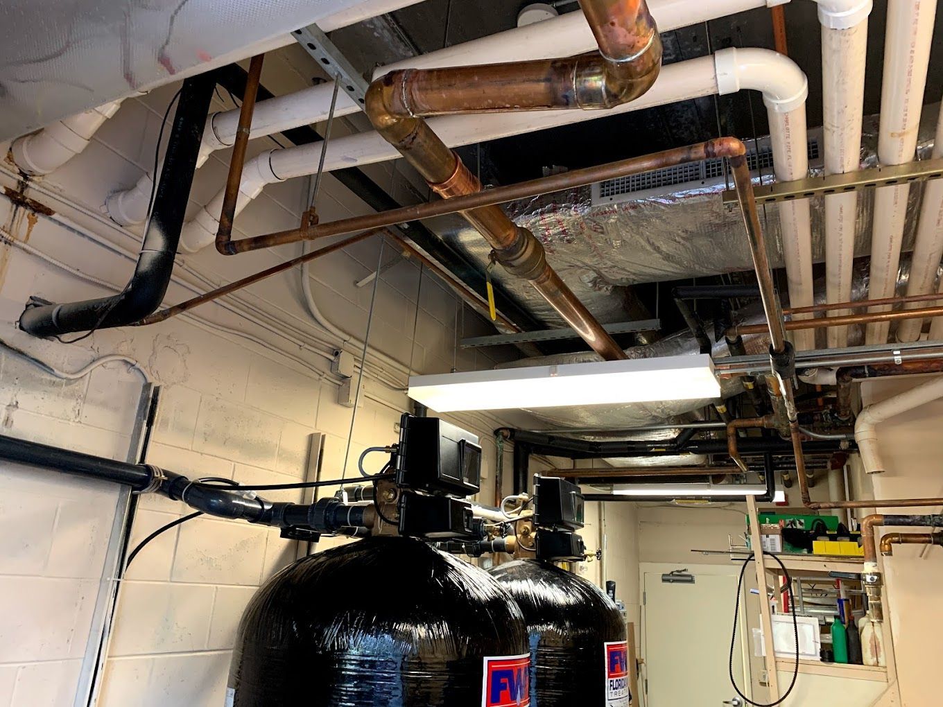 There are a lot of pipes hanging from the ceiling in this room.