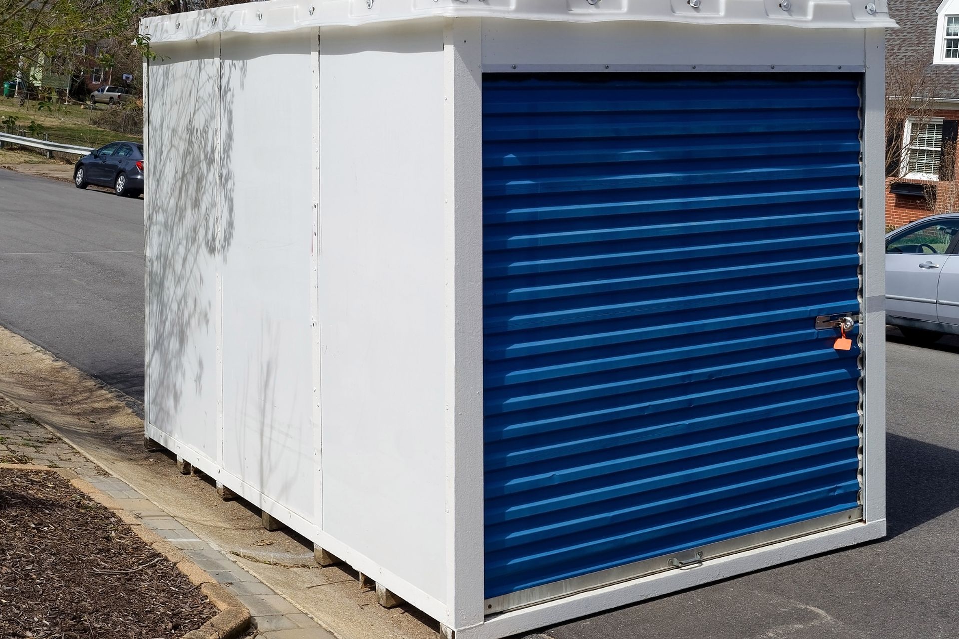 White storage unit with blue rolling door on a street.