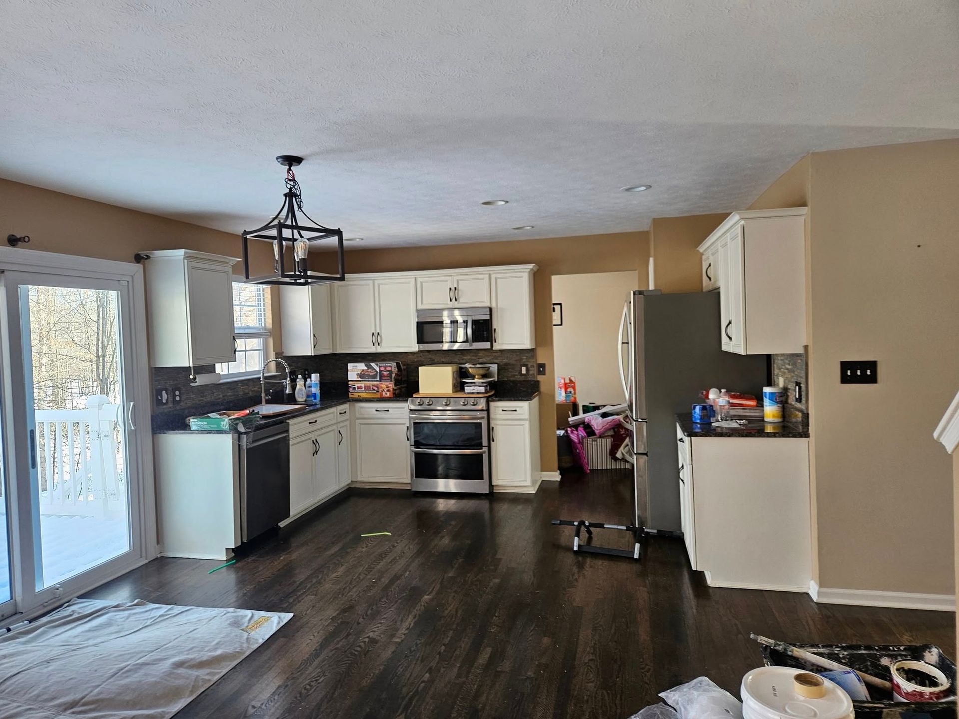 Kitchen with white cabinets, dark wood floor, stainless steel appliances, and a snow-covered view.