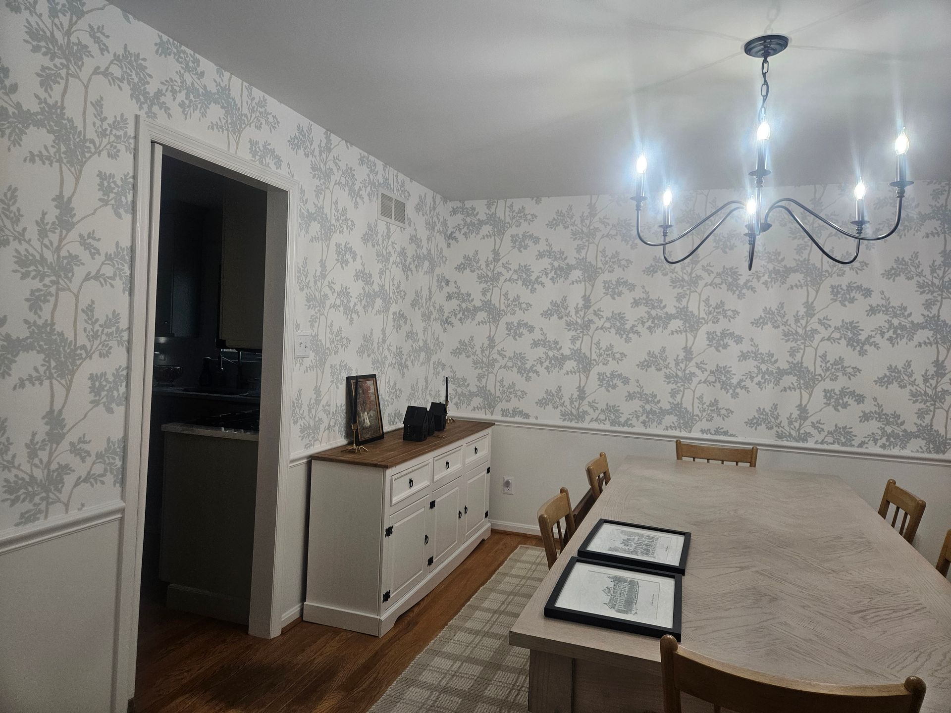 Person on ladder, using drill to work on drywall around skylight. Interior setting with wood beam.