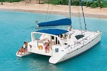 A group of people are sitting on the back of a sailboat in the ocean.