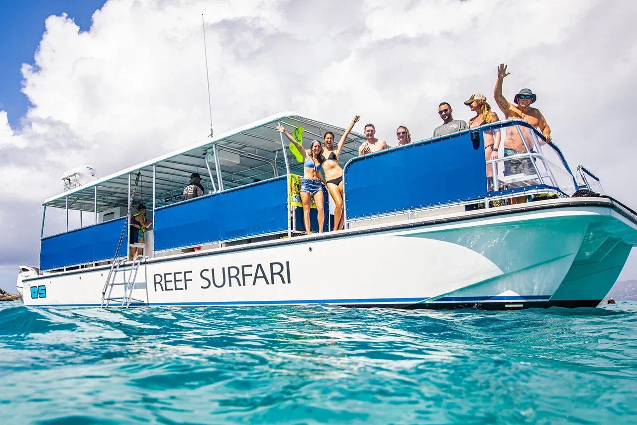 A group of people are standing on top of a boat in the ocean.