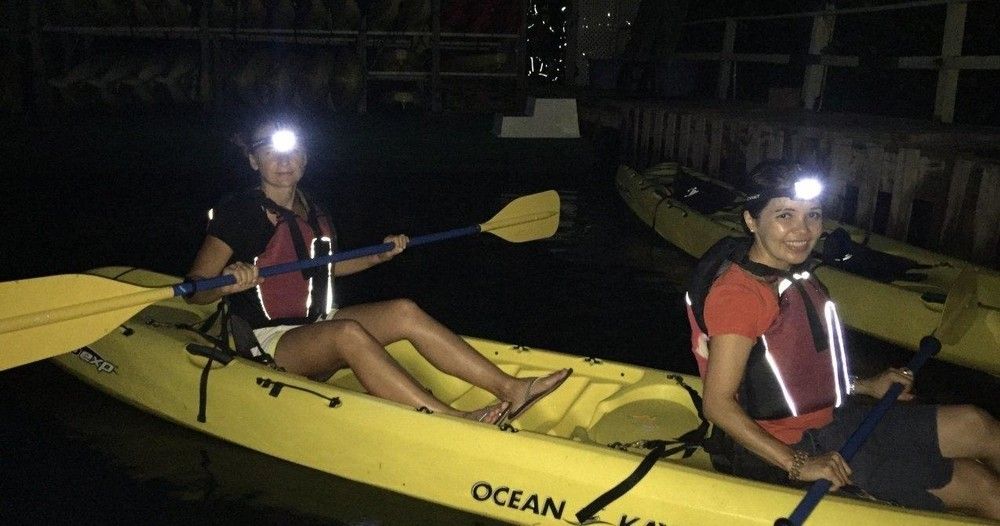 Two people are in a yellow ocean kayak at night