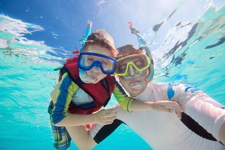 A man and a boy are taking a selfie underwater in the ocean.